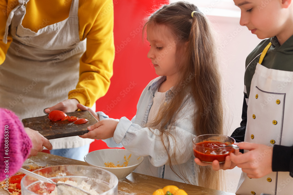 Little children preparing pizza during cooking class in kitchen