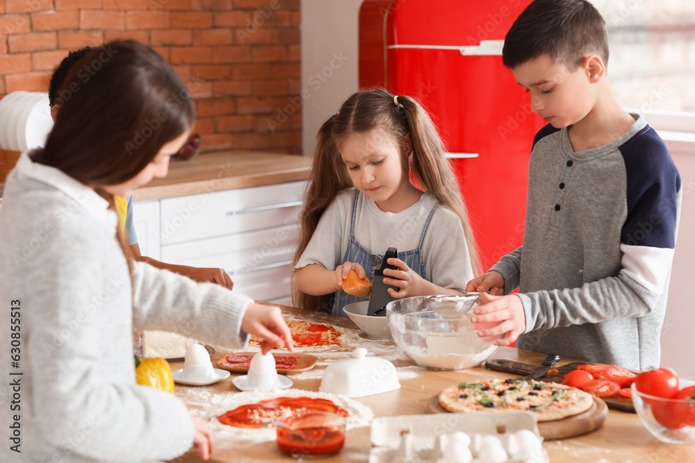 Little children preparing pizza during cooking class in kitchen