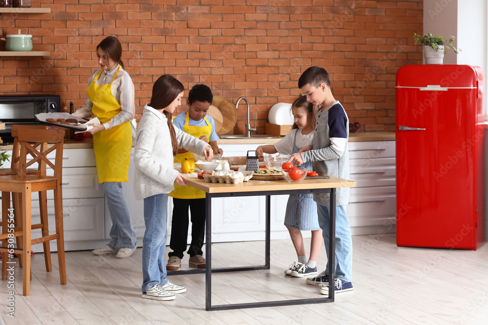 Little children preparing pizza during cooking class in kitchen