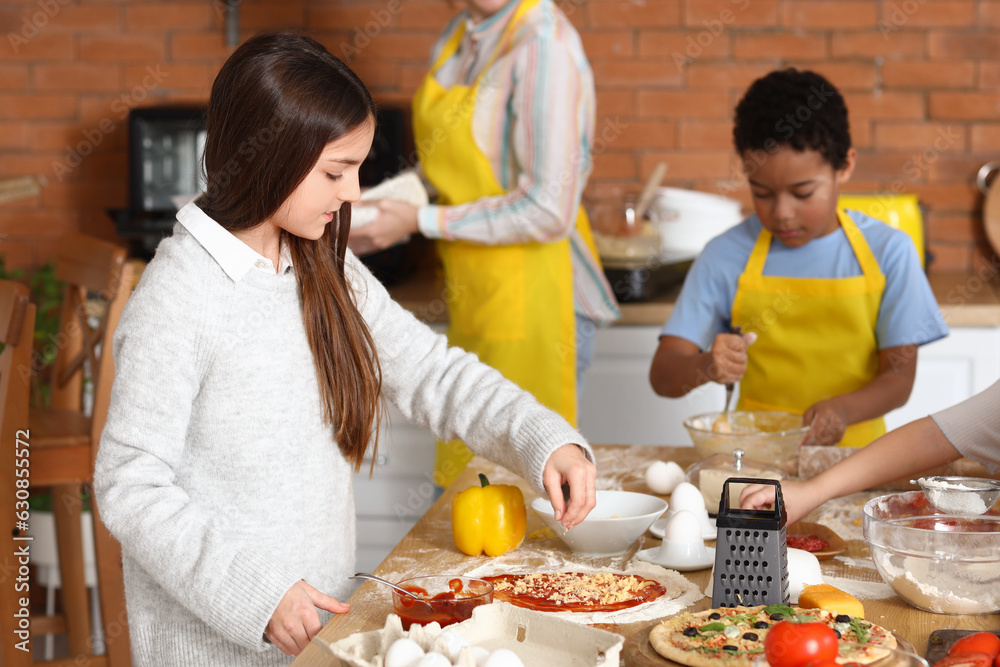 Little girl preparing pizza during cooking class in kitchen