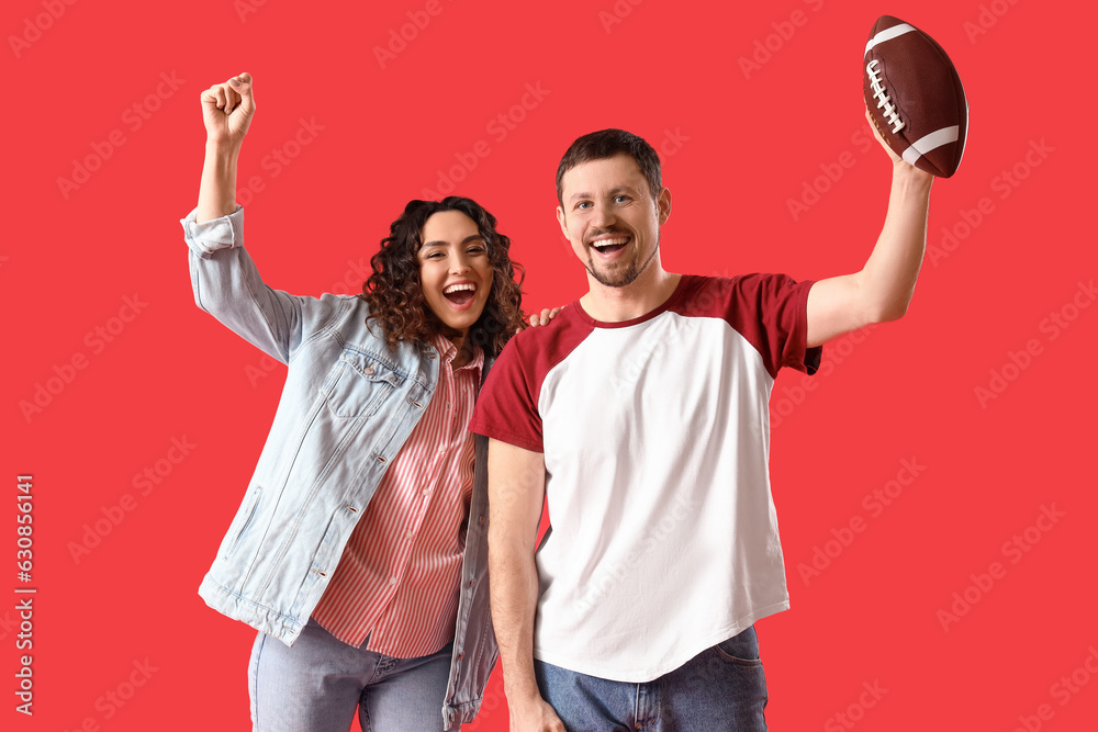 Happy young couple with rugby ball on red background