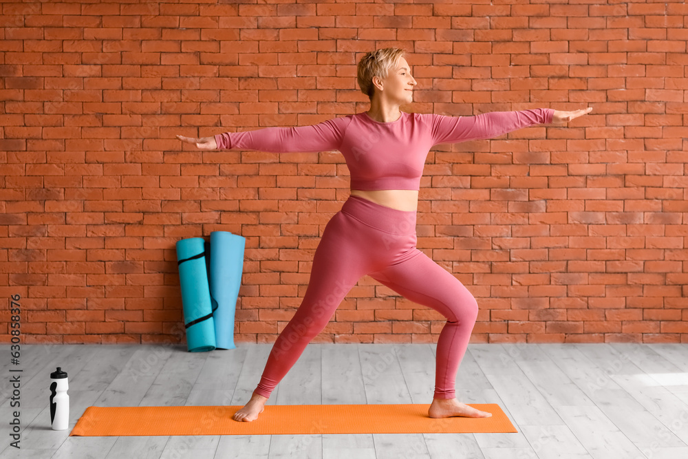 Sporty mature woman practicing yoga in  gym