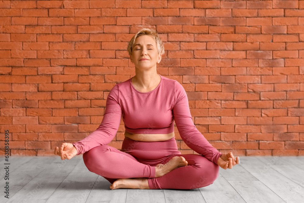 Sporty mature woman practicing yoga in  gym