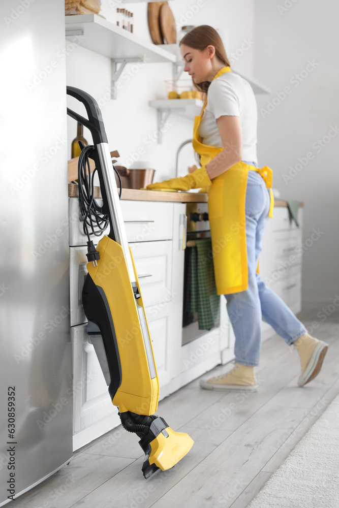 Young woman cleaning counter in kitchen