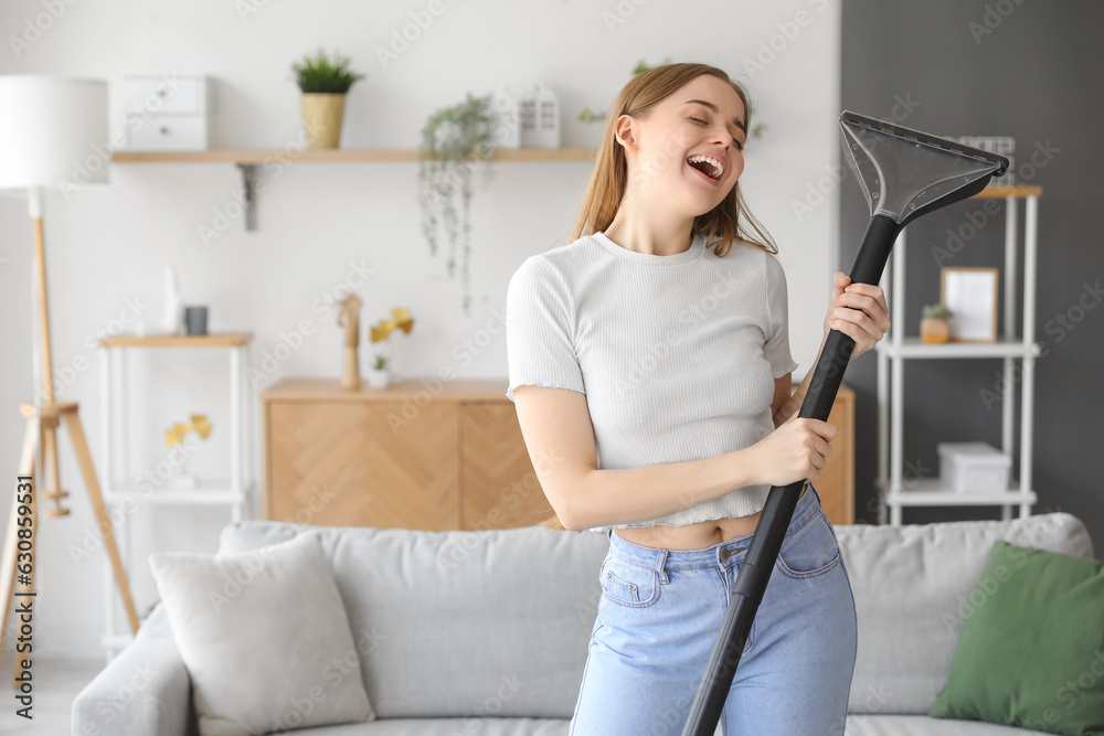 Young woman with vacuum cleaner singing at home