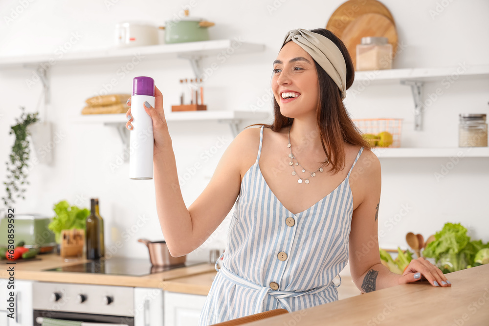 Young woman with air freshener in kitchen