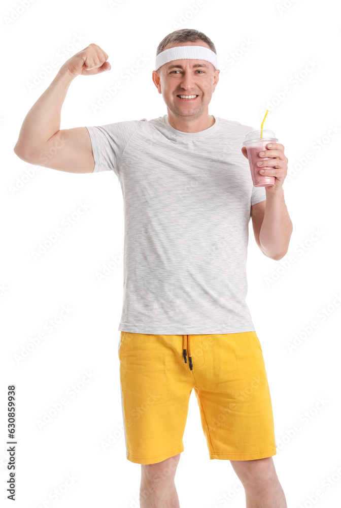 Sporty mature man with glass of fruit smoothie showing muscles on white background