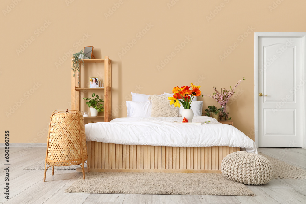 Interior of stylish living room with tulip flowers in vase on bed