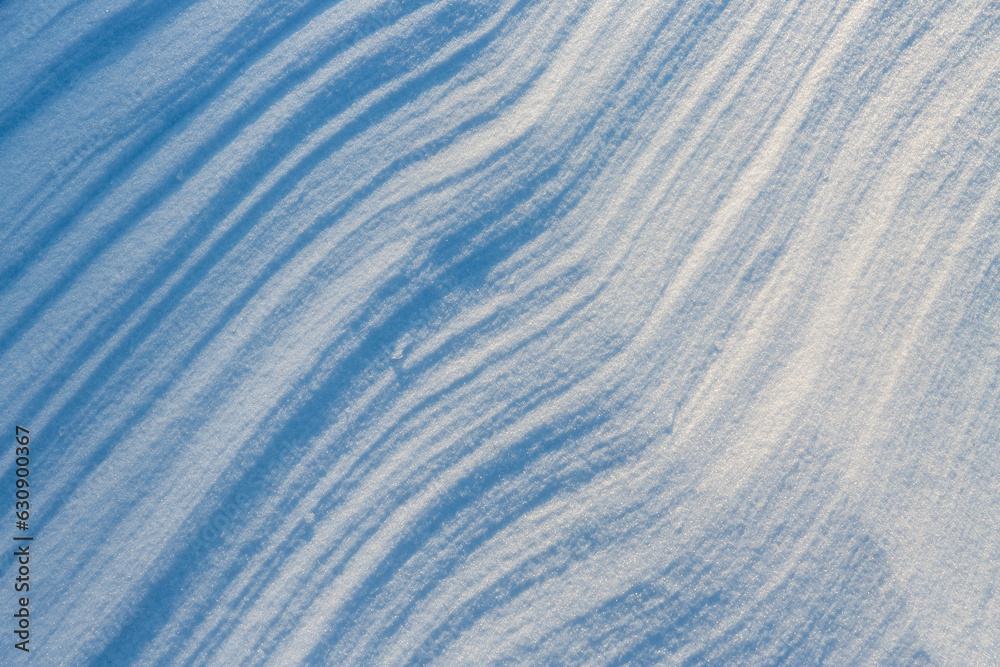 Beautiful winter background with snowy ground. Natural snow texture. Wind sculpted patterns on snow 