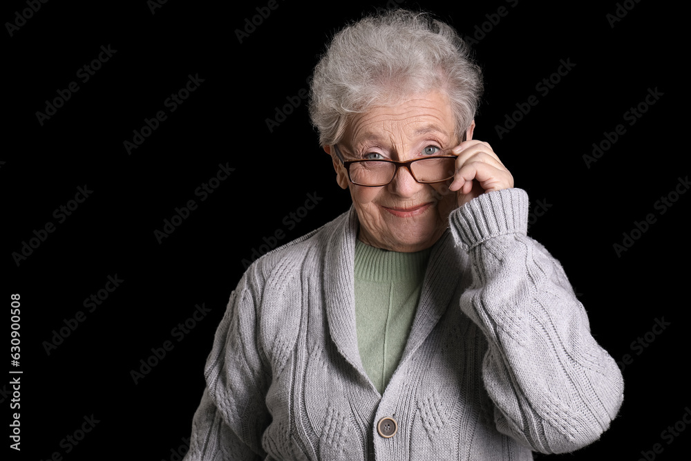 Senior woman in eyeglasses on black background