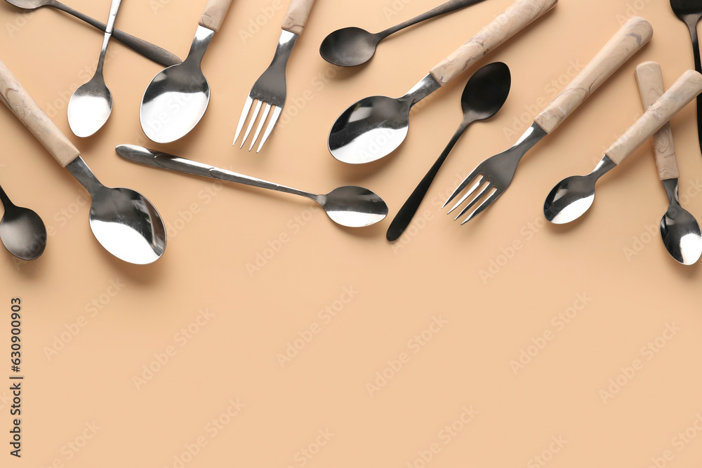 Silver and black cutlery on beige background