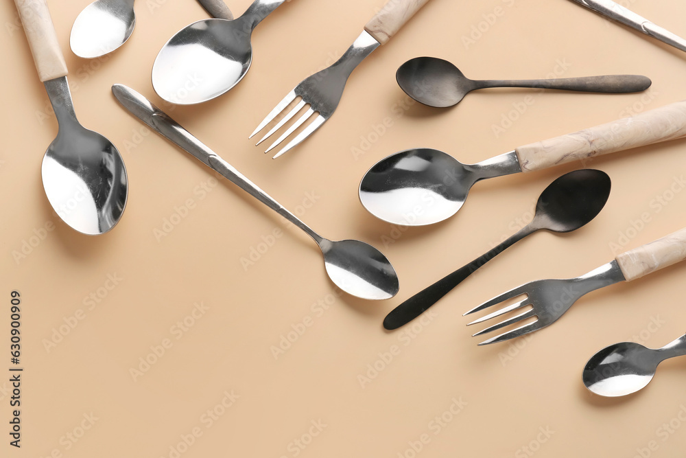 Silver and black cutlery on beige background