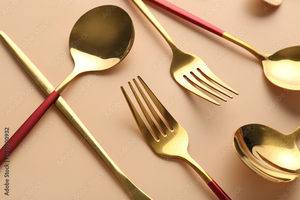 Golden cutlery on beige background