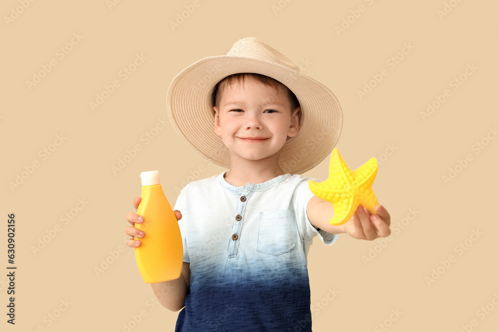 Little boy with starfish toy and bottle of sunscreen cream on beige background