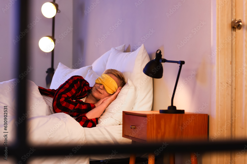 Mature woman with mask sleeping in bed at night