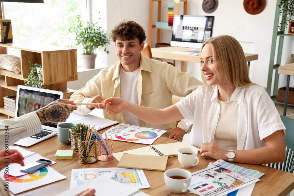 Team of graphic designers working with color palettes at table in office