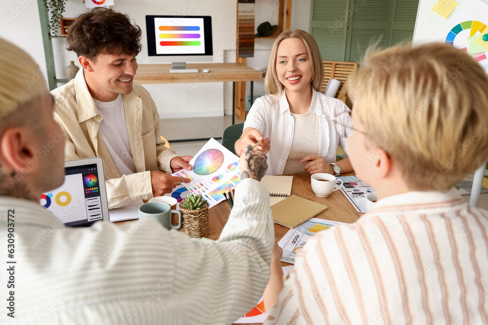 Team of graphic designers working with color palettes at table in office