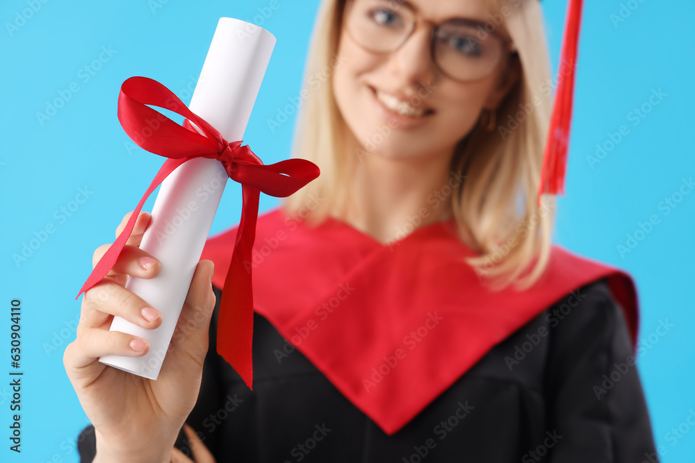 Female graduate student with diploma on blue background, closeup