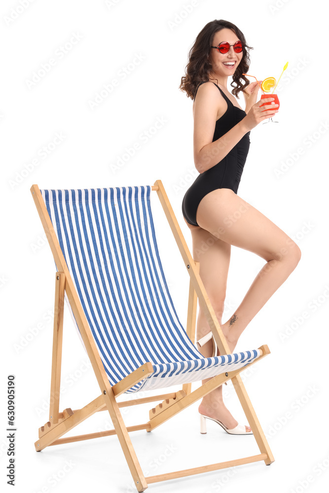 Young woman with cocktail and deck chair on white background