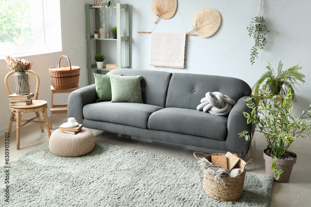 Interior of light living room with sofa, wicker basket and houseplants