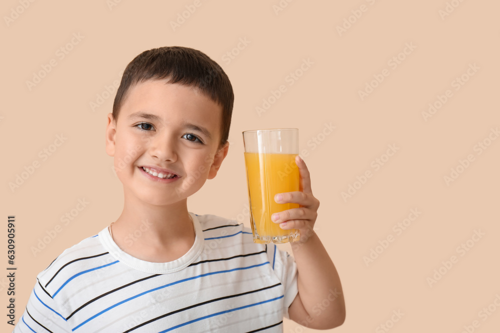 Cute little boy with glass of orange juice on beige background, closeup