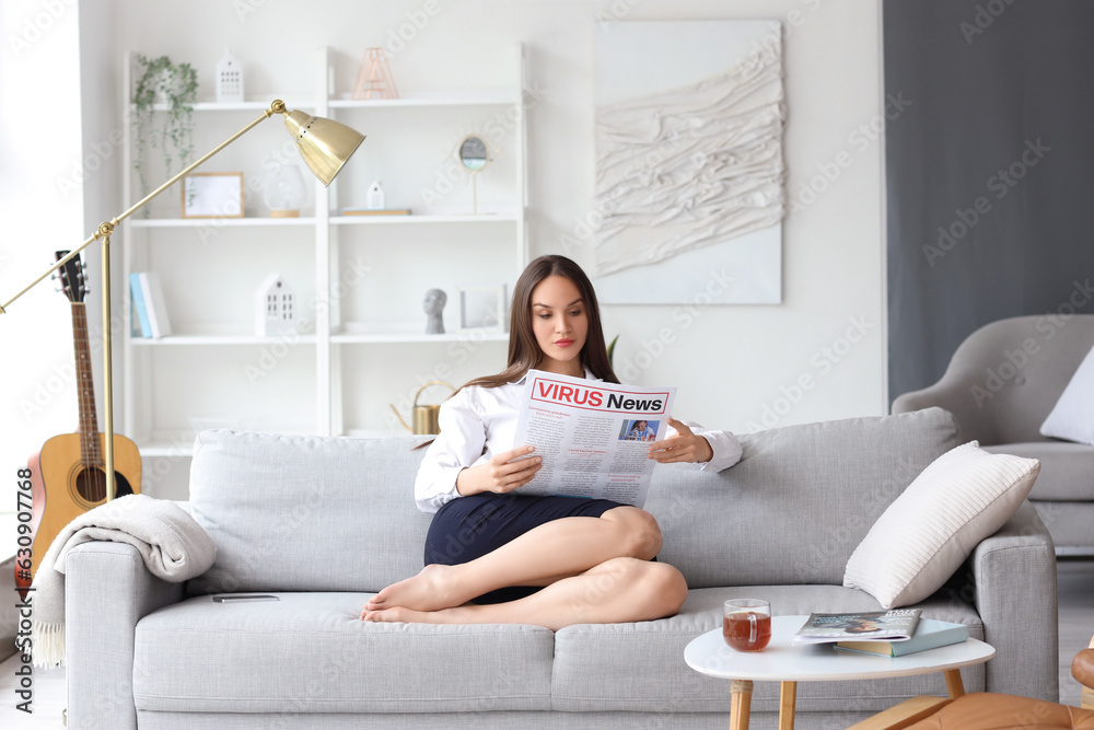 Young businesswoman reading newspaper at home after long working day