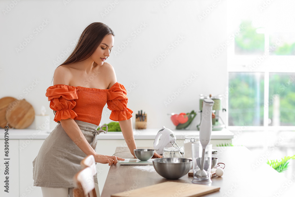 Young woman preparing dough in kitchen