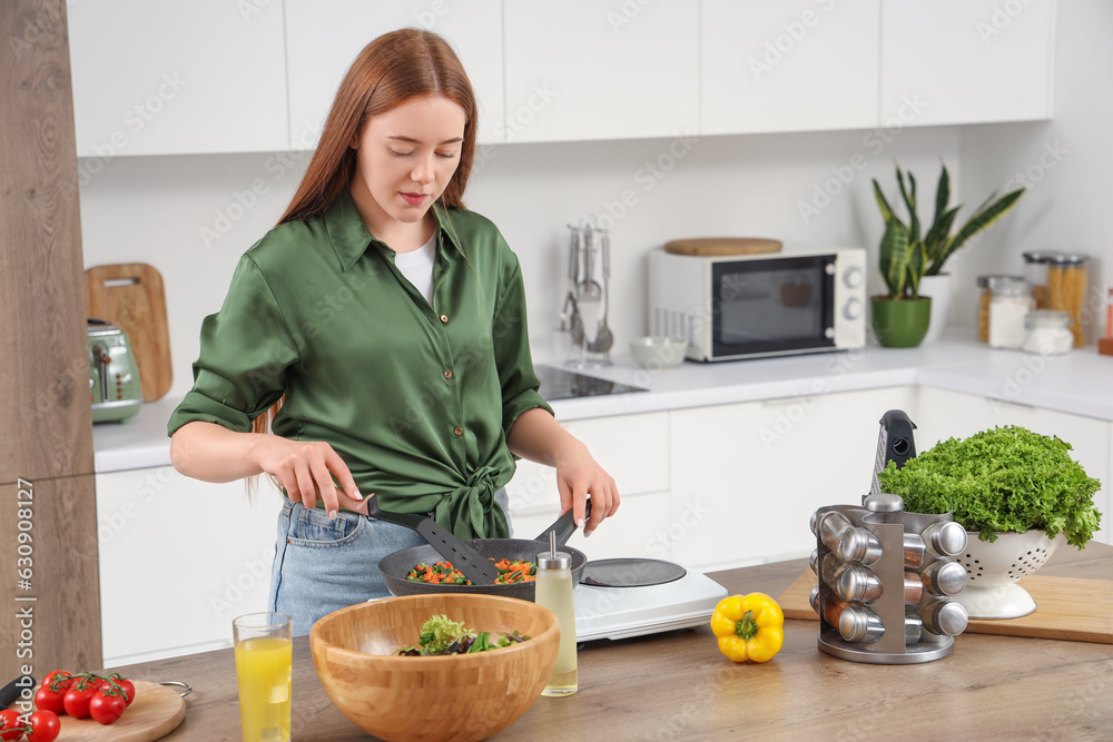 Young woman frying vegetables in kitchen