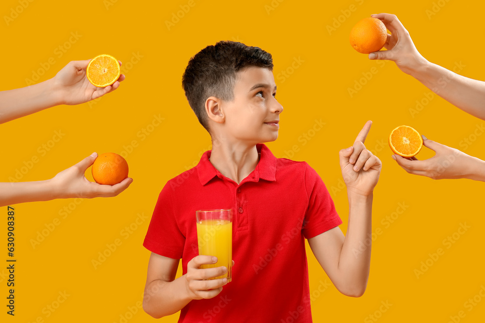 Little boy with glass of juice pointing at orange on color background