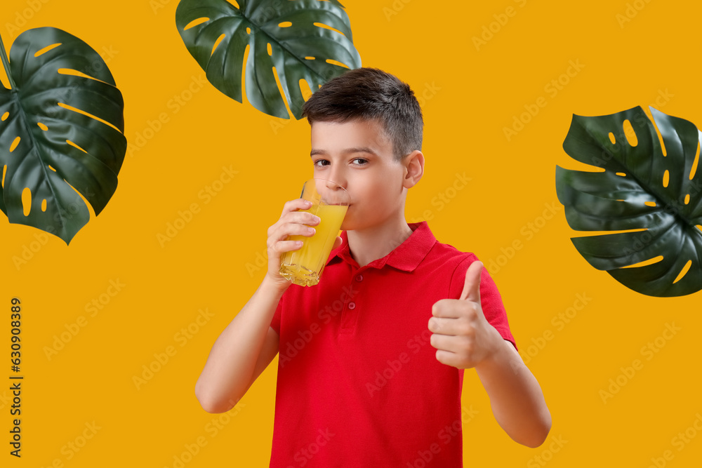 Little boy with glass of orange juice and palm leaves showing thumb-up on color background