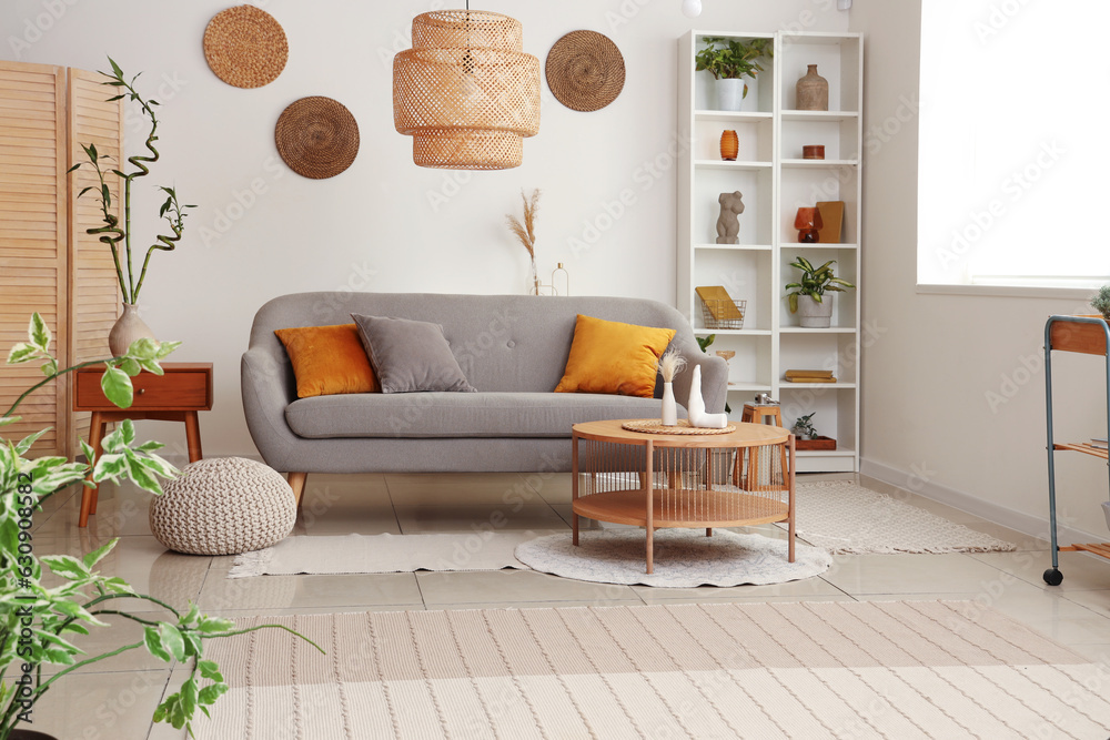 Interior of light living room with grey sofa, coffee table and houseplants