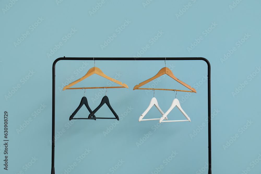 Rack with wooden clothes hangers on blue background