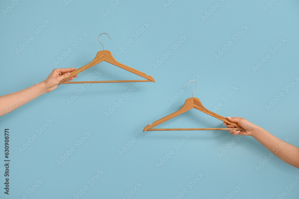 Woman holding wooden clothes hangers on blue background