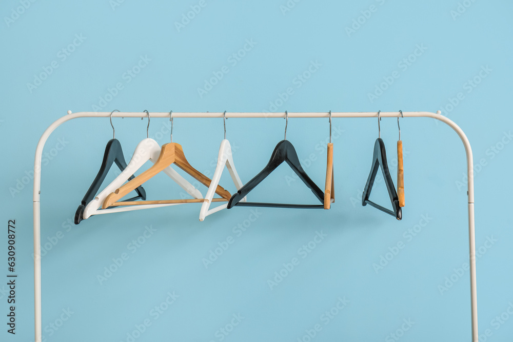 Rack with wooden clothes hangers on blue background