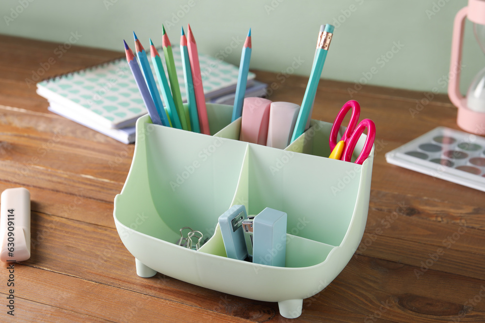 Holder with different stationery on wooden table