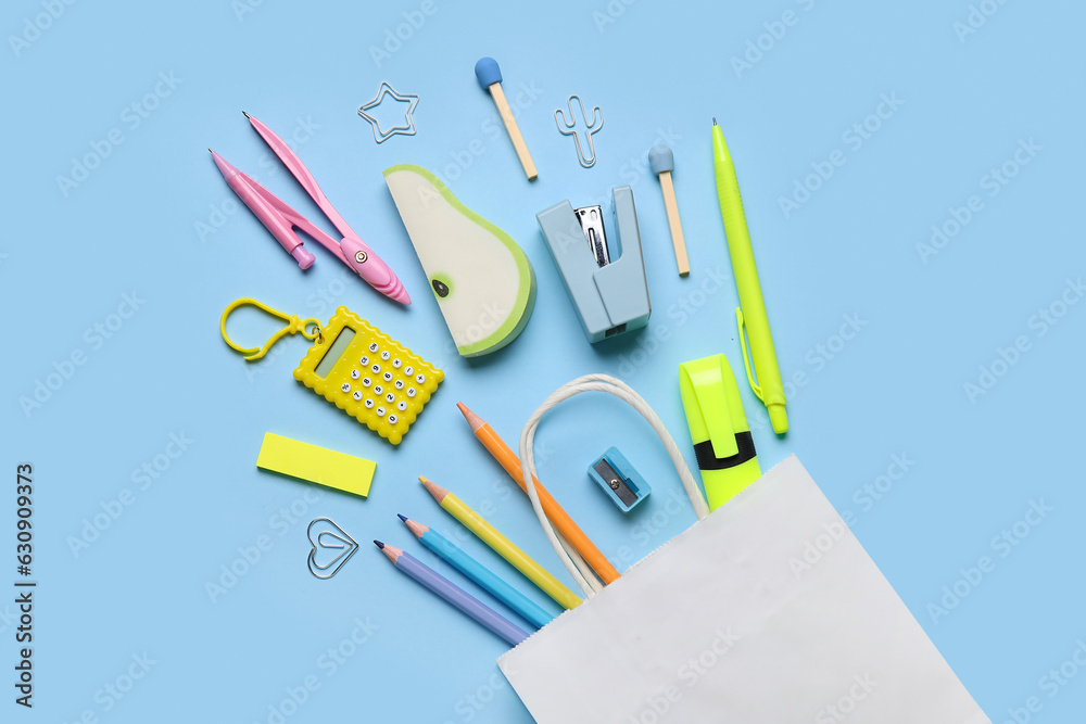 Composition with paper bag and colorful stationery on color background