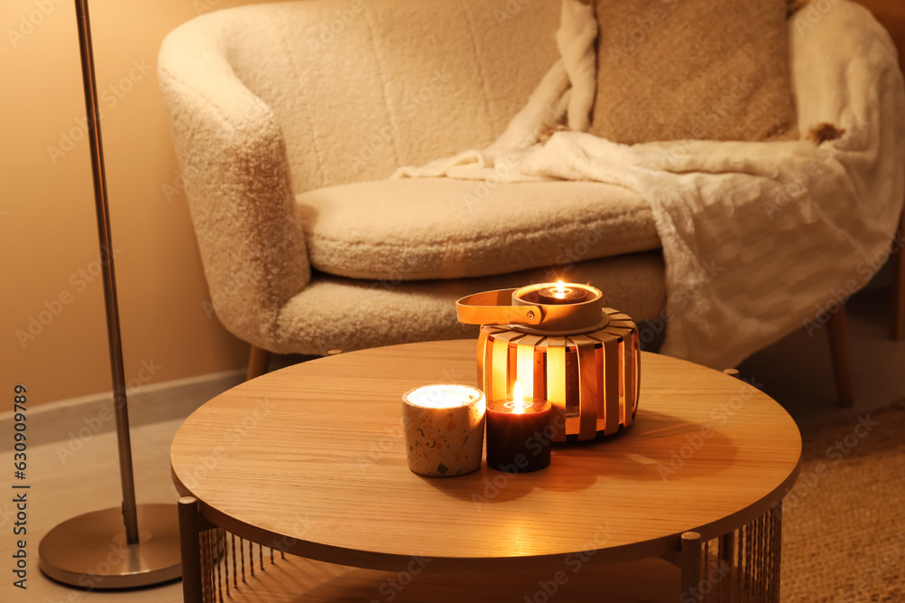 Burning candles on table in living room