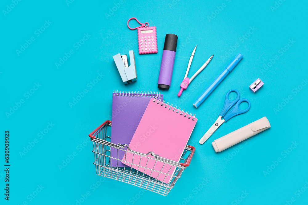 Shopping basket with different school stationery on blue background