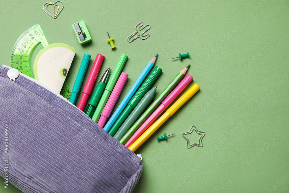 Pencil case with different school stationery on green background, closeup