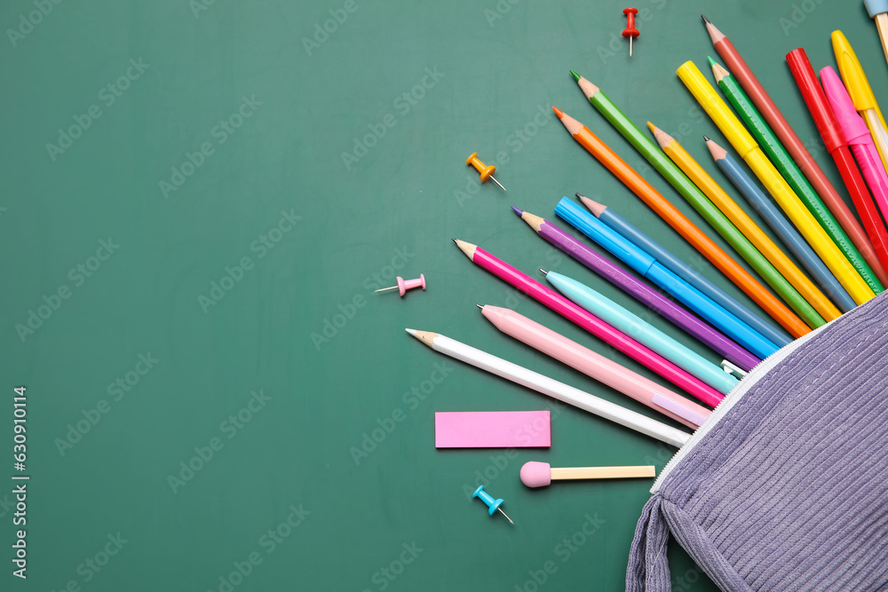 Pencil case with different school stationery on green background