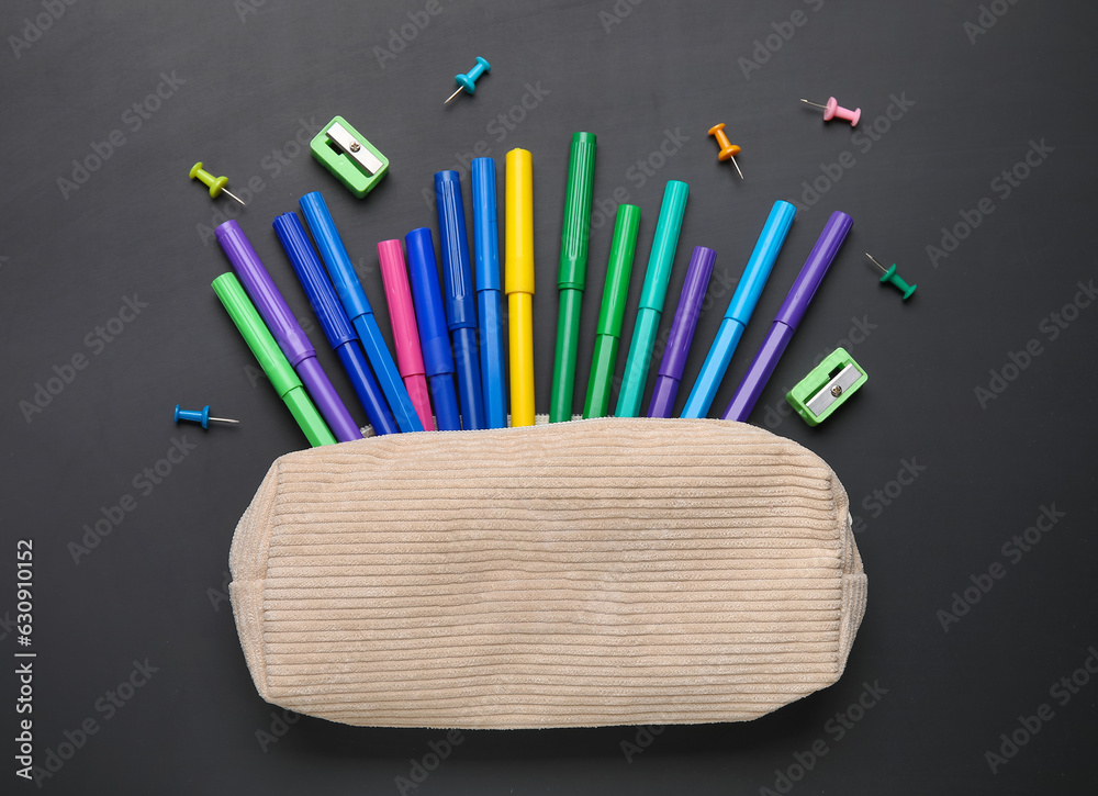 Pencil case with different school stationery on black background