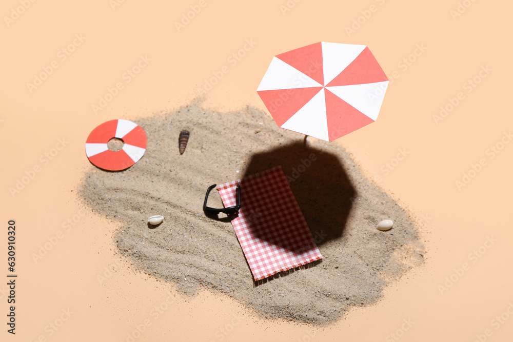 Creative summer composition with mini umbrella, beach accessories and sand on beige background