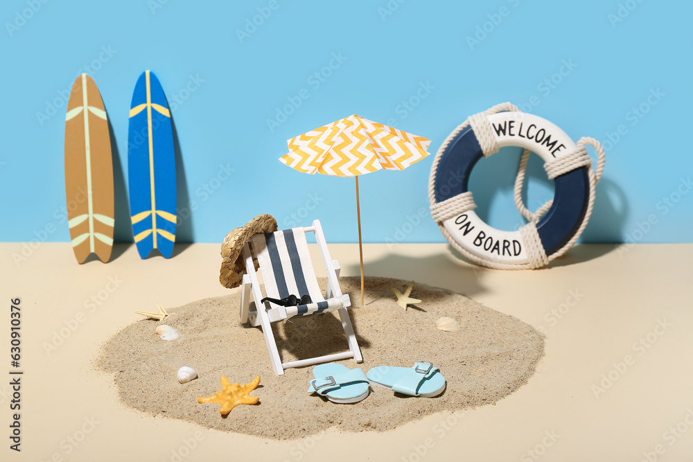 Creative summer composition with mini umbrella, deckchair and beach accessories on color background