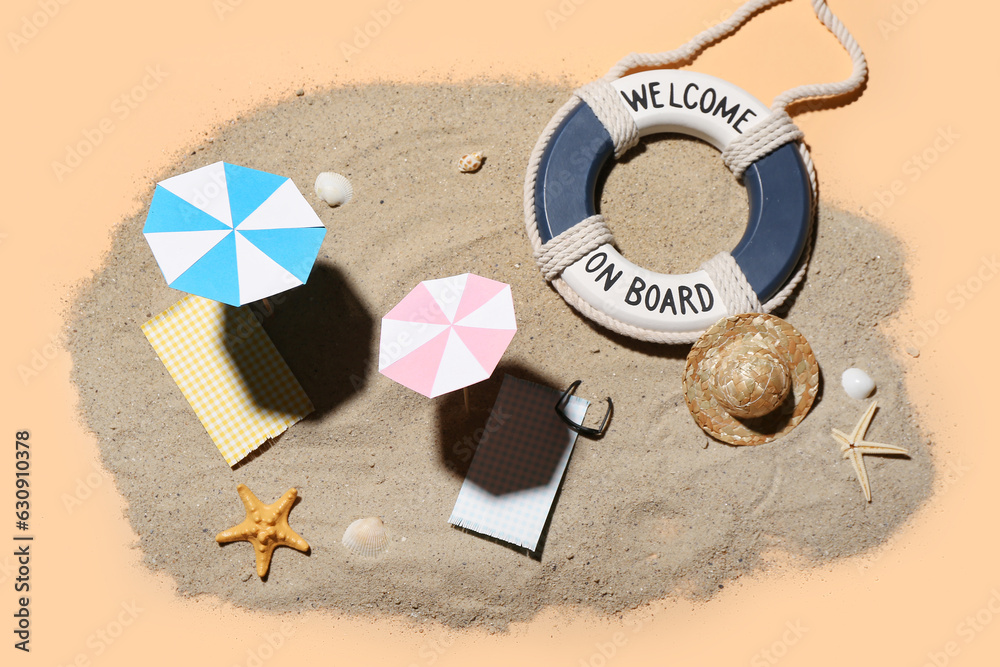 Creative summer composition with mini umbrellas, beach accessories and sand on beige background