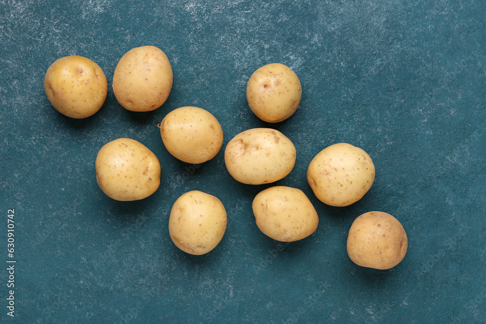 Fresh raw potatoes on blue background