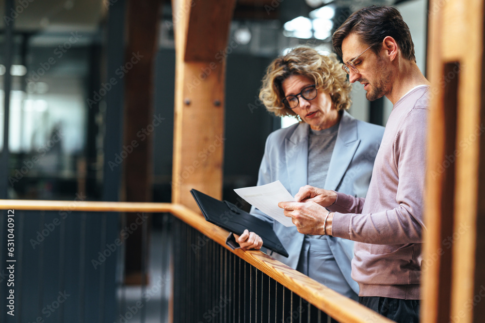 Two business colleagues discussing a document in an office