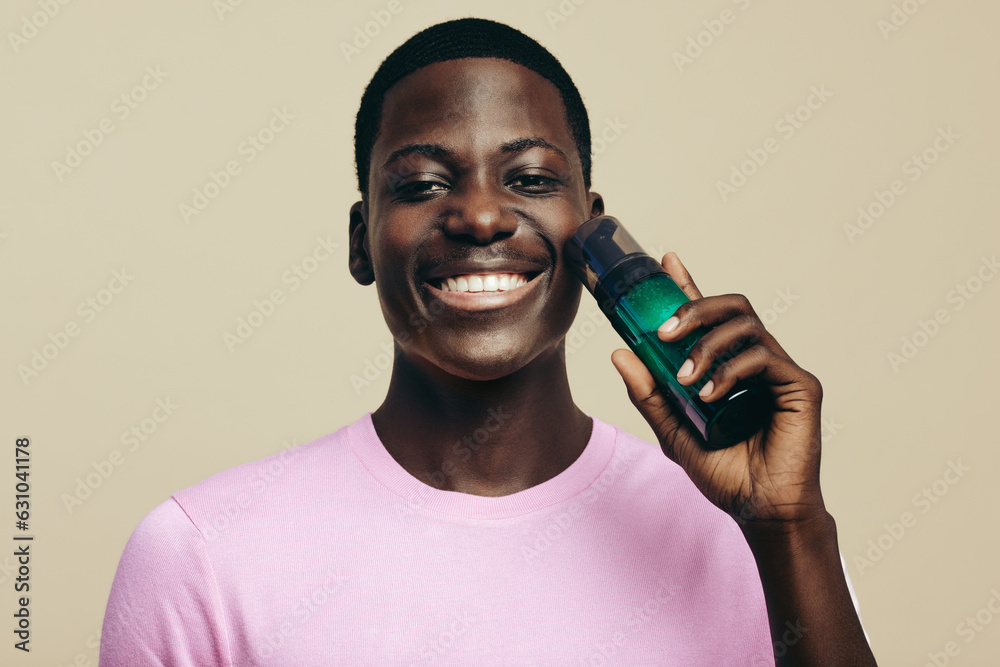 Face wash for melanin skin. Happy black man holding a facial beauty product in a studio