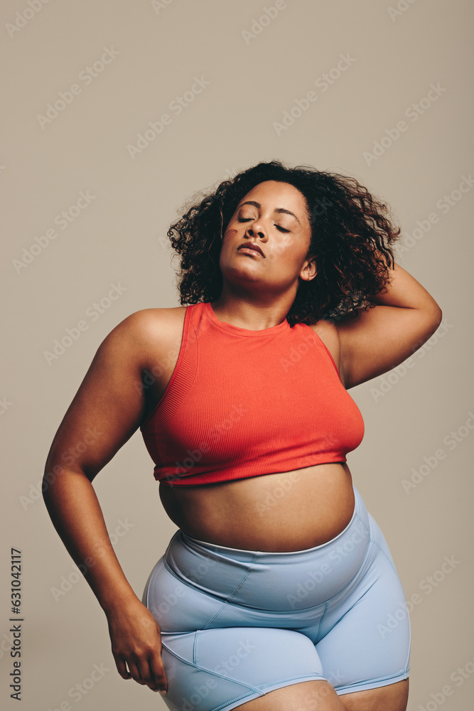 Confident woman with a fit body stands in a studio in fitness wear