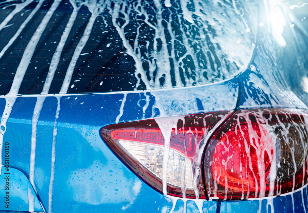 Blue car wash with white soap foam and professional auto care service. Car cleaning service concept.