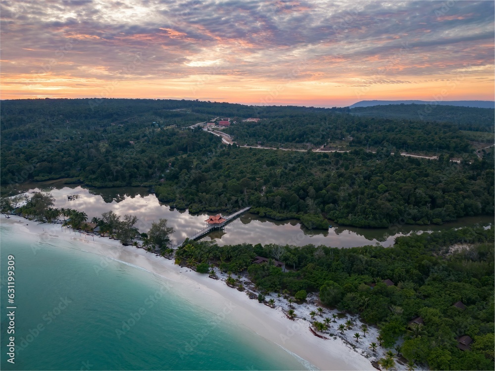 Aerial view of Koh Rong beach surrounded by dense trees during sunset